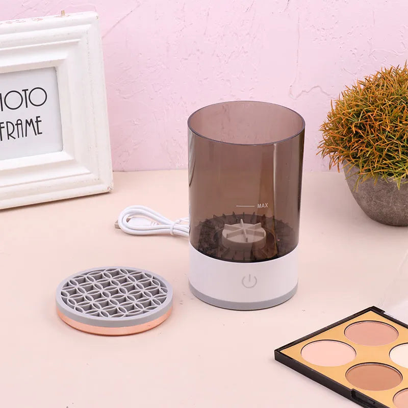Grey and white portable electric makeup brush cleaner with USB charging cable.