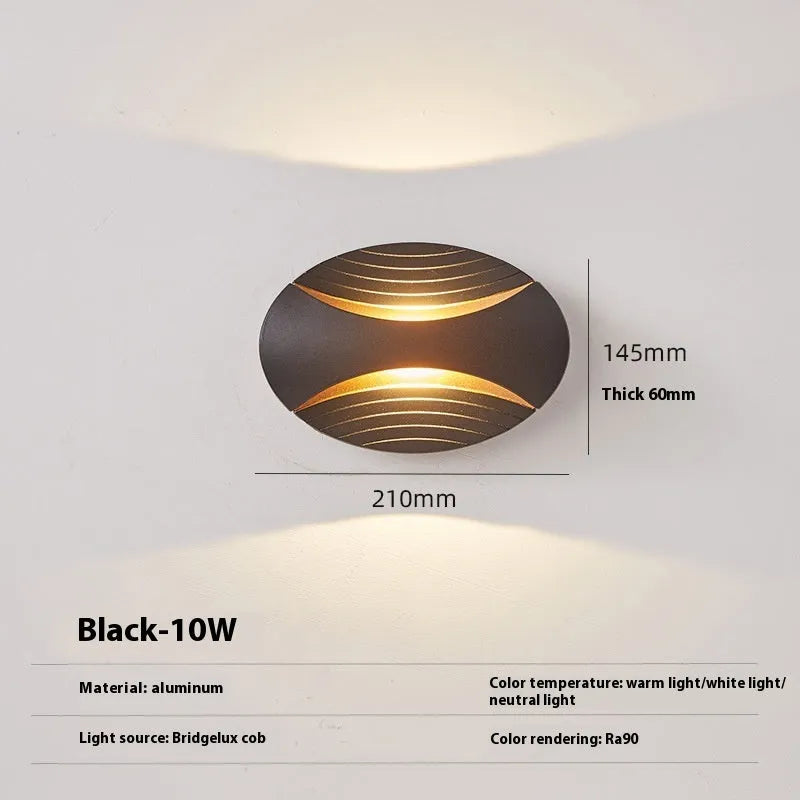 Modern aluminium wall lamp in black finish mounted beside a bed, emitting warm LED light.