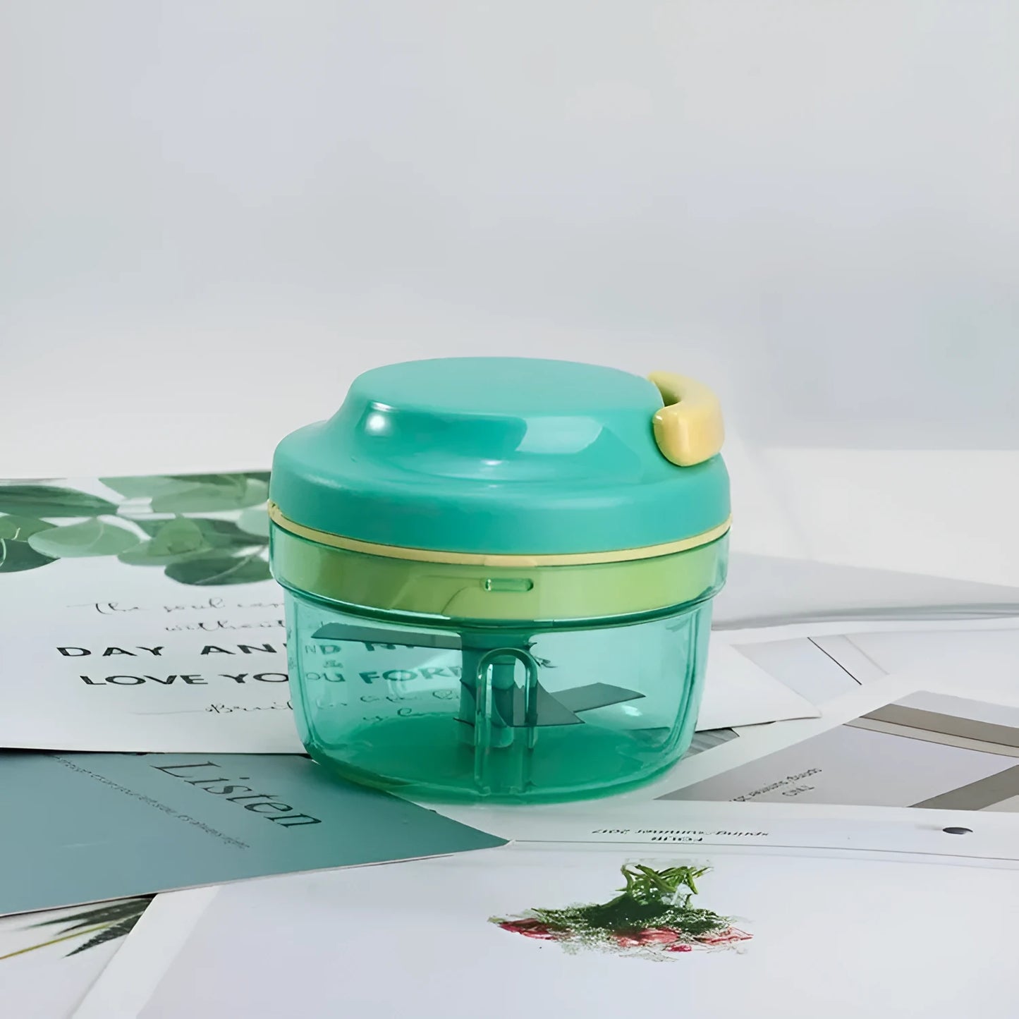 Green manual food chopper with pull cord, stainless steel blade, and 300ml transparent container.