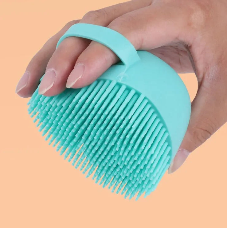 Blue silicone dog bath and massage brush held in a hand.