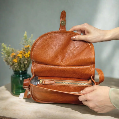 Genuine leather messenger bag in brown colour showing flap closure and textured cowhide material