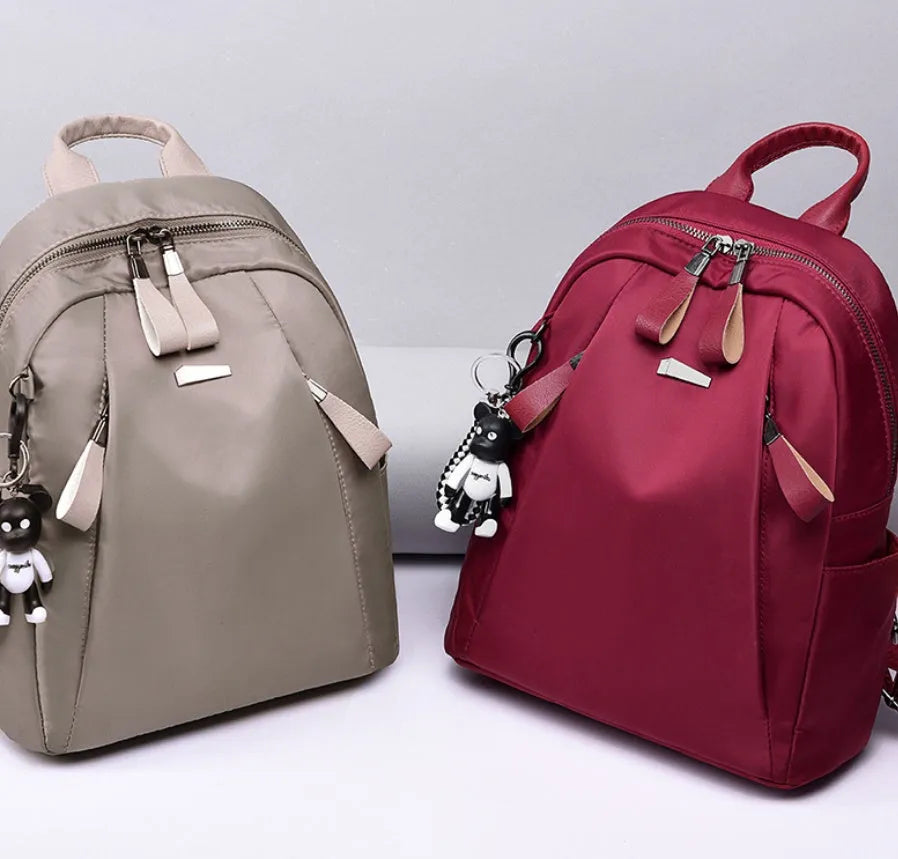 Medium square rucksack in Oxford cloth with two straps and a soft handle, shown in wine red.