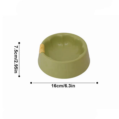 Green plastic double pet bowl with two compartments for food and water on a flat surface.