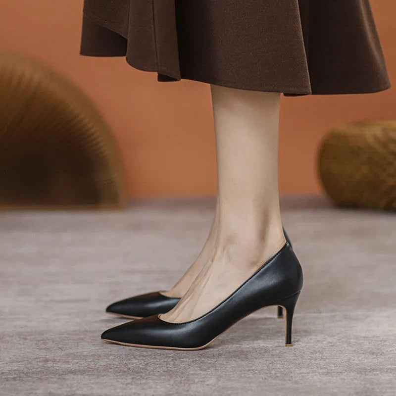 Black pointed toe stiletto high heel shoe with a low cut vamp on a white background.