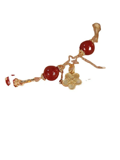 Red agate double layer bracelet with flower and peach blossom charms on a wrist.