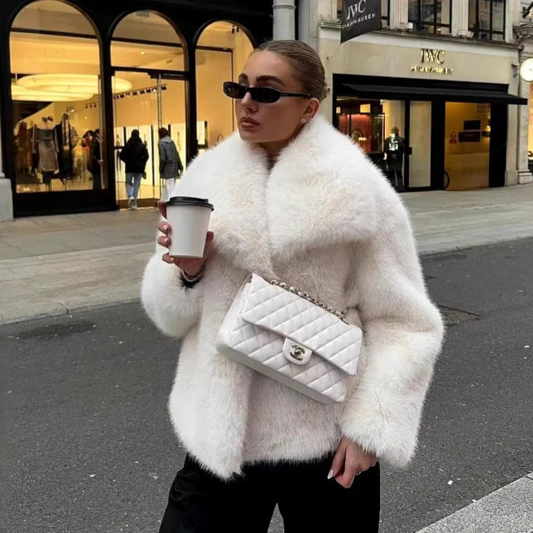 Women's white artificial fur coat with large lapel, long sleeves, and deep pockets shown in street fashion setting