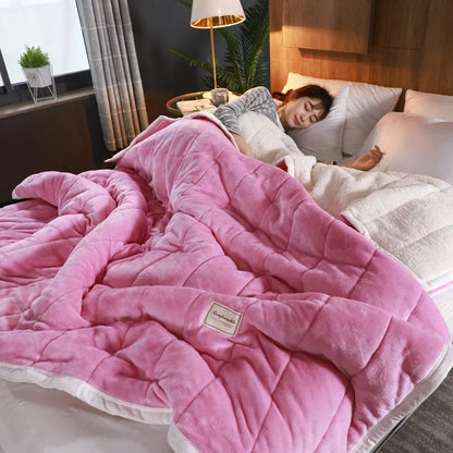 Thick pink coral fleece blanket folded on a twin bed.