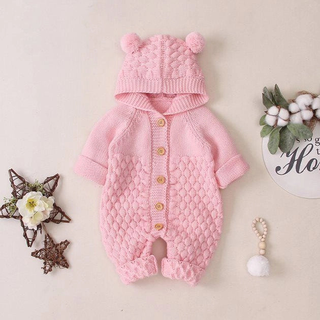 Baby wearing light blue knitted romper with hood and sleeveless design, single-breasted closure visible