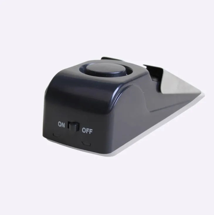 Portable wedge-shaped door stop alarm unit with stainless steel cover and sensitivity controls.
