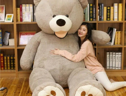 A giant, plush teddy bear in a variety of sizes and colors, including light brown, dark brown, gray, white, pink, and purple.
