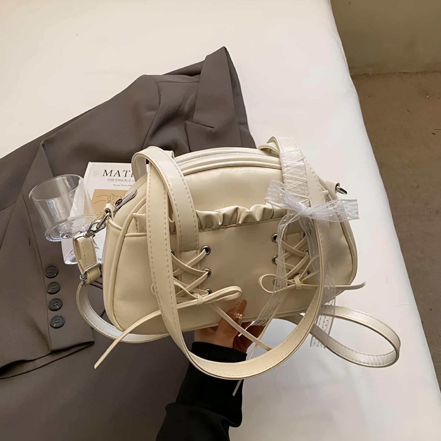 Milky white women's shoulder handbag with a large bandage bow and visible stitching, showing the internal phone pocket.