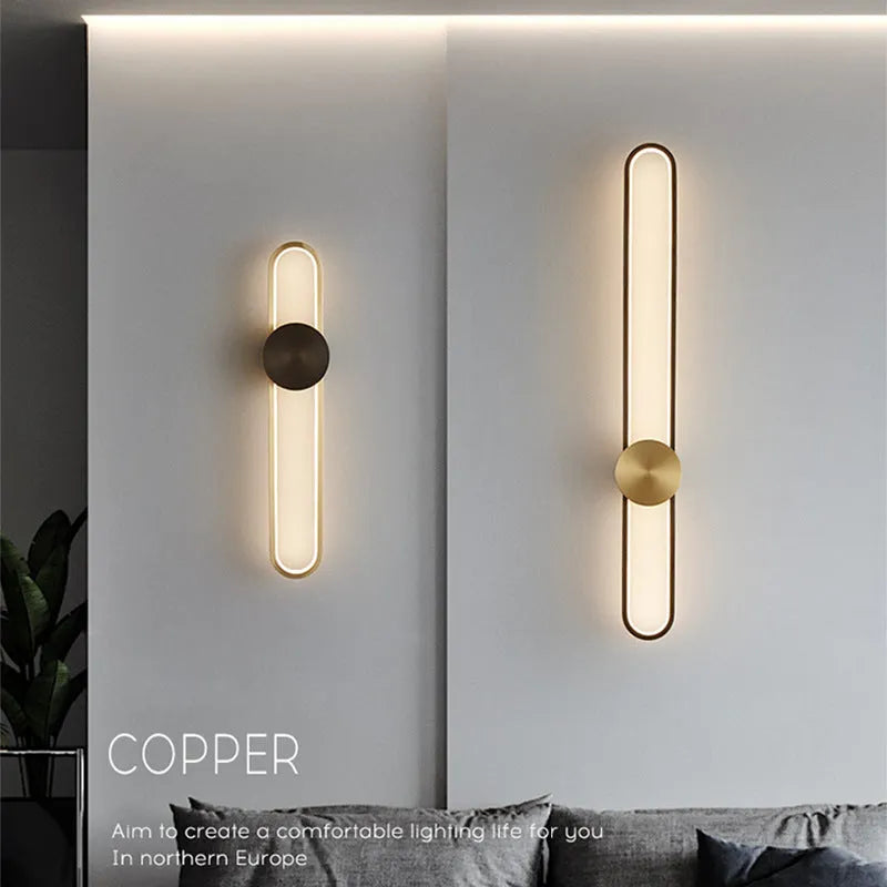 Round black iron wall sconce with integrated LED light glowing on a modern grey wall
