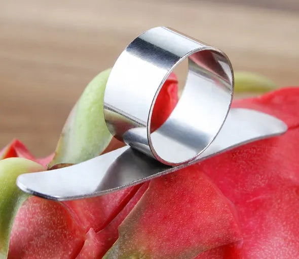 Silver stainless steel citrus fruit peeler with a ring handle on a wooden surface.