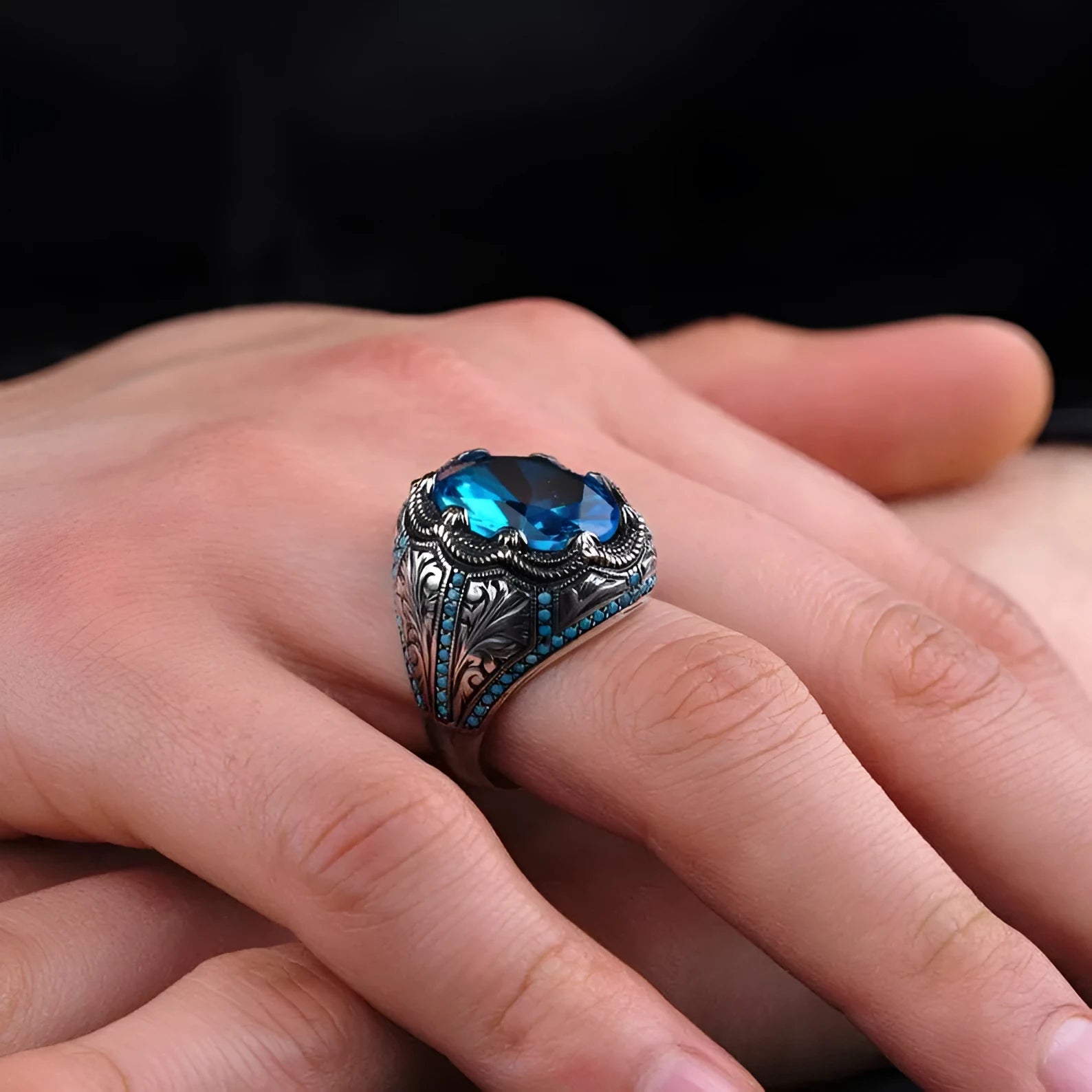 Close-up of a blue zircon geometric grandmother ring in antique silver on a finger.