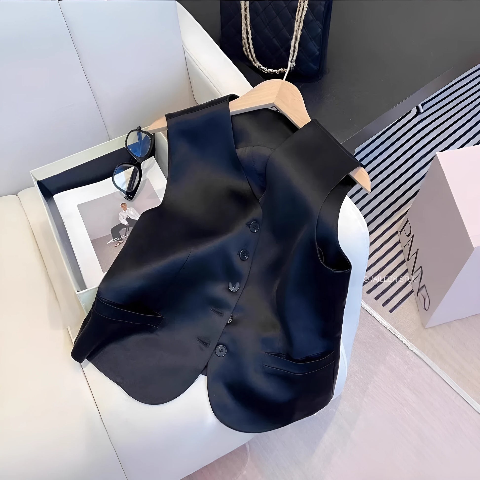 Black satin sleeveless vest for women on a hanger, showing loose fit and splicing detail.