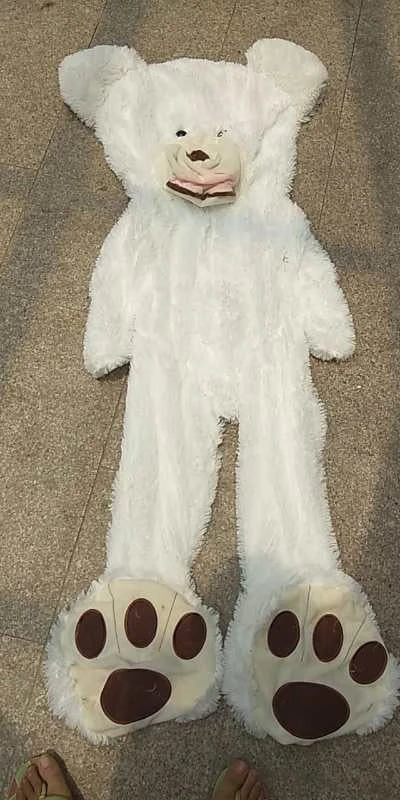 A giant, plush teddy bear in a variety of sizes and colors, including light brown, dark brown, gray, white, pink, and purple.