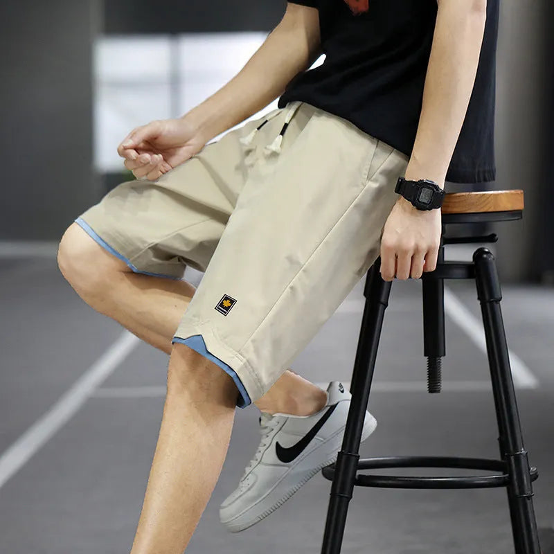 Man wearing loose straight-leg beach shorts in khaki, showcasing the South Korean style fit and micro-elastic waistband.