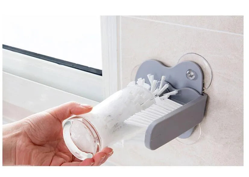 Grey rotating double-head cup brush with suction cups for wall mounting.