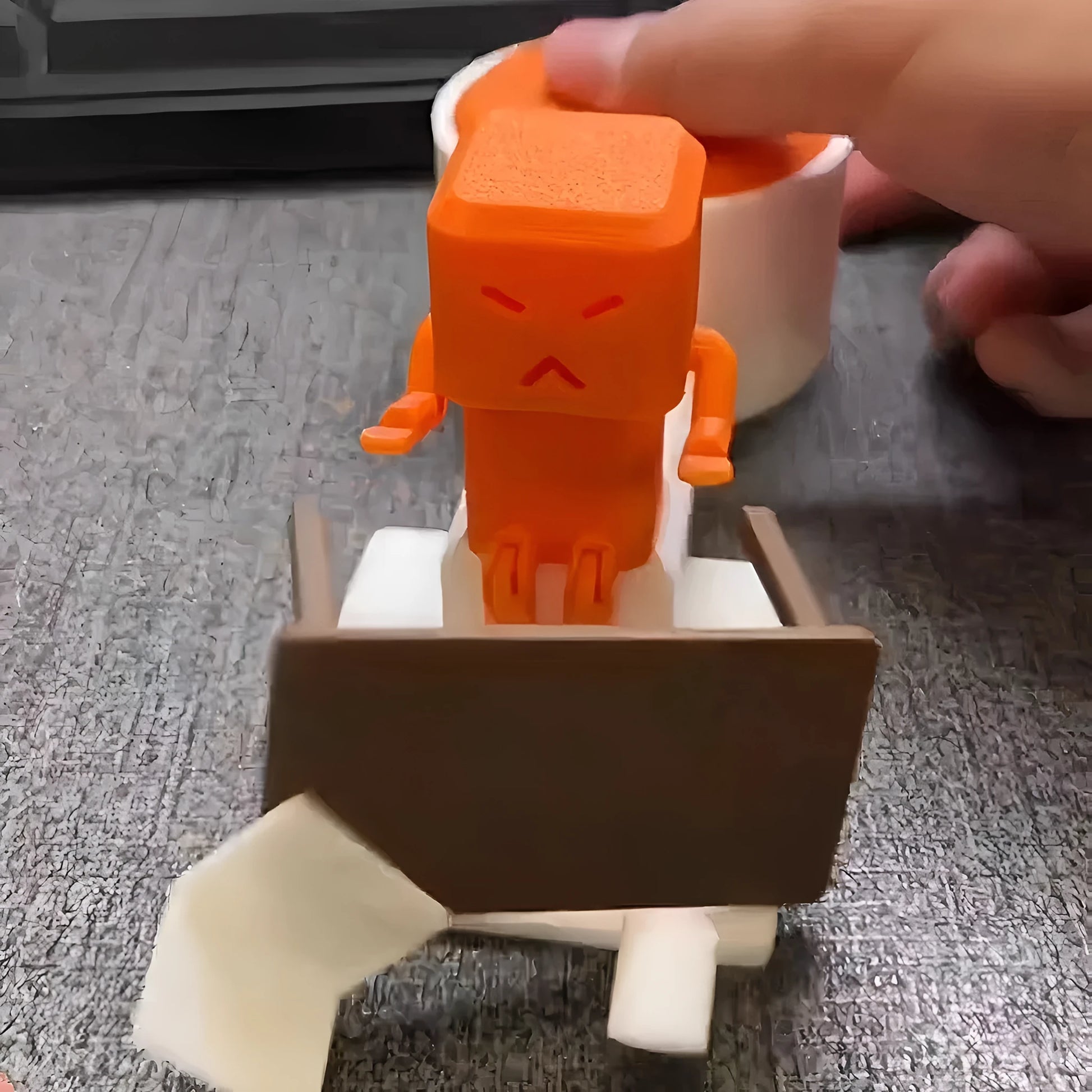 Orange plastic vent decompression toy with turning table mechanism on a desk.