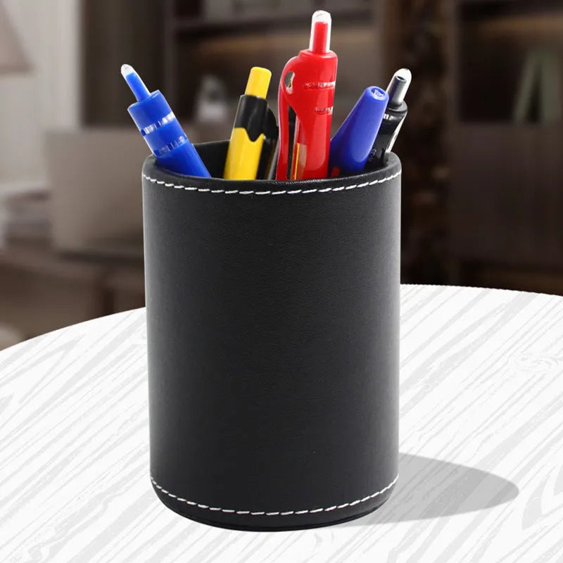 Round black leather pen container measuring 8.0cm diameter by 10.8cm height on wooden desk