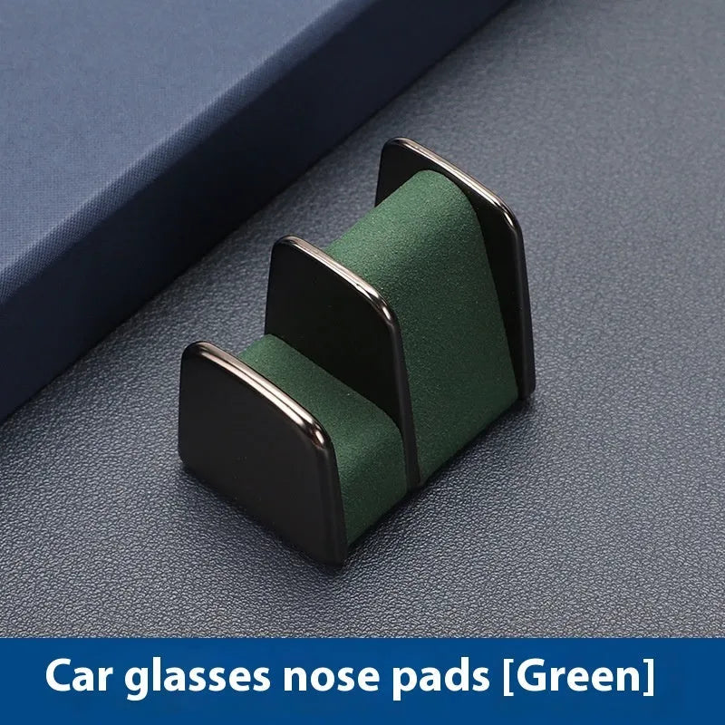 Green zinc alloy and leather glasses clip holder attached to a car dashboard, holding sunglasses.