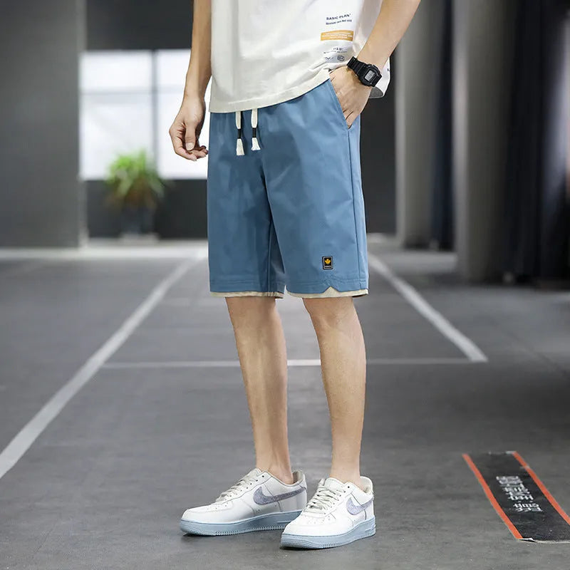 Man wearing loose straight-leg beach shorts in khaki, showcasing the South Korean style fit and micro-elastic waistband.