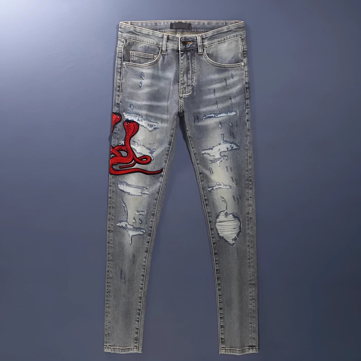 Men's slim fit blue jeans with washed-out finish, hole patches, and embroidery detail.