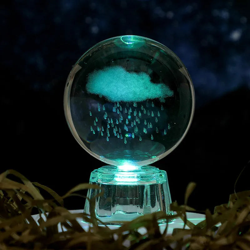 Transparent crystal ball ornament with inner carving of clouds, shown on a wooden table.