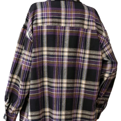 A woman modelling a loose-fit black, green, and purple plaid shirt with long sleeves.