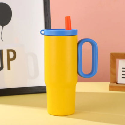 Large pink insulated straw cup with a black handle and push-button lid on a wooden table