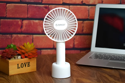 White ORICO FH1 portable USB desk fan with rechargeable battery on a wooden desk