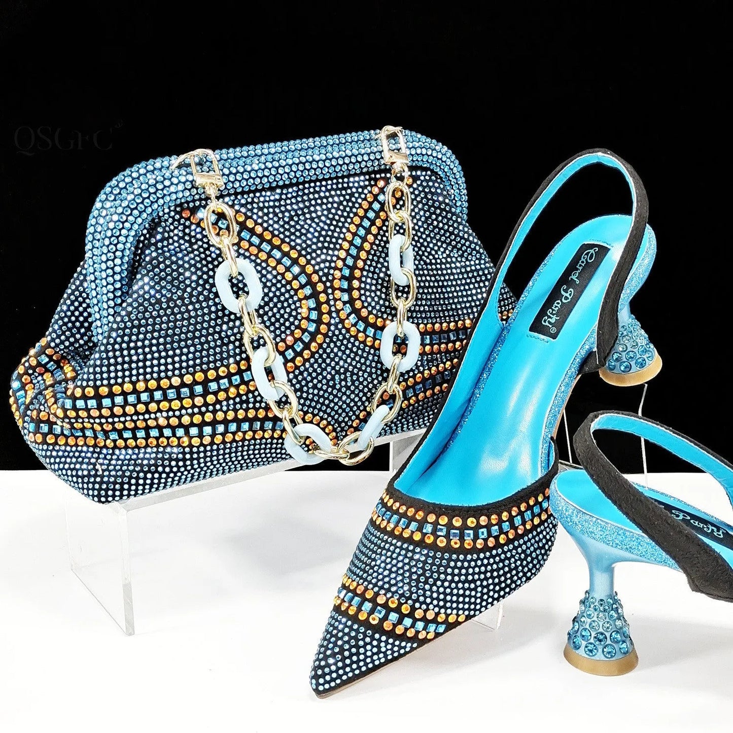 Women's pointed toe high heel court shoes in blue with rhinestone detail and a matching small bag.