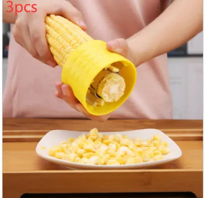 Yellow manual corn grinder thresher with corn-shaped design and stainless steel gear for peeling corn kernels.