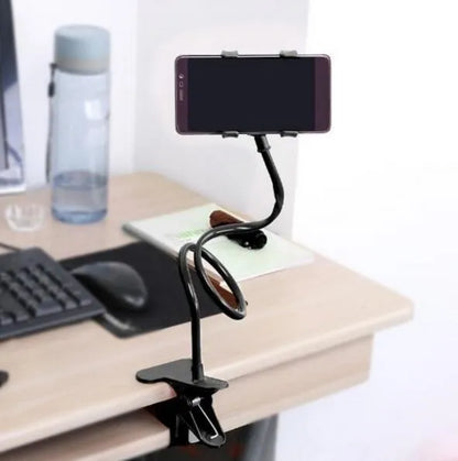 Black flexible arm mobile phone holder with V-clip gripping a smartphone, extended to 70cm on a bedside table.