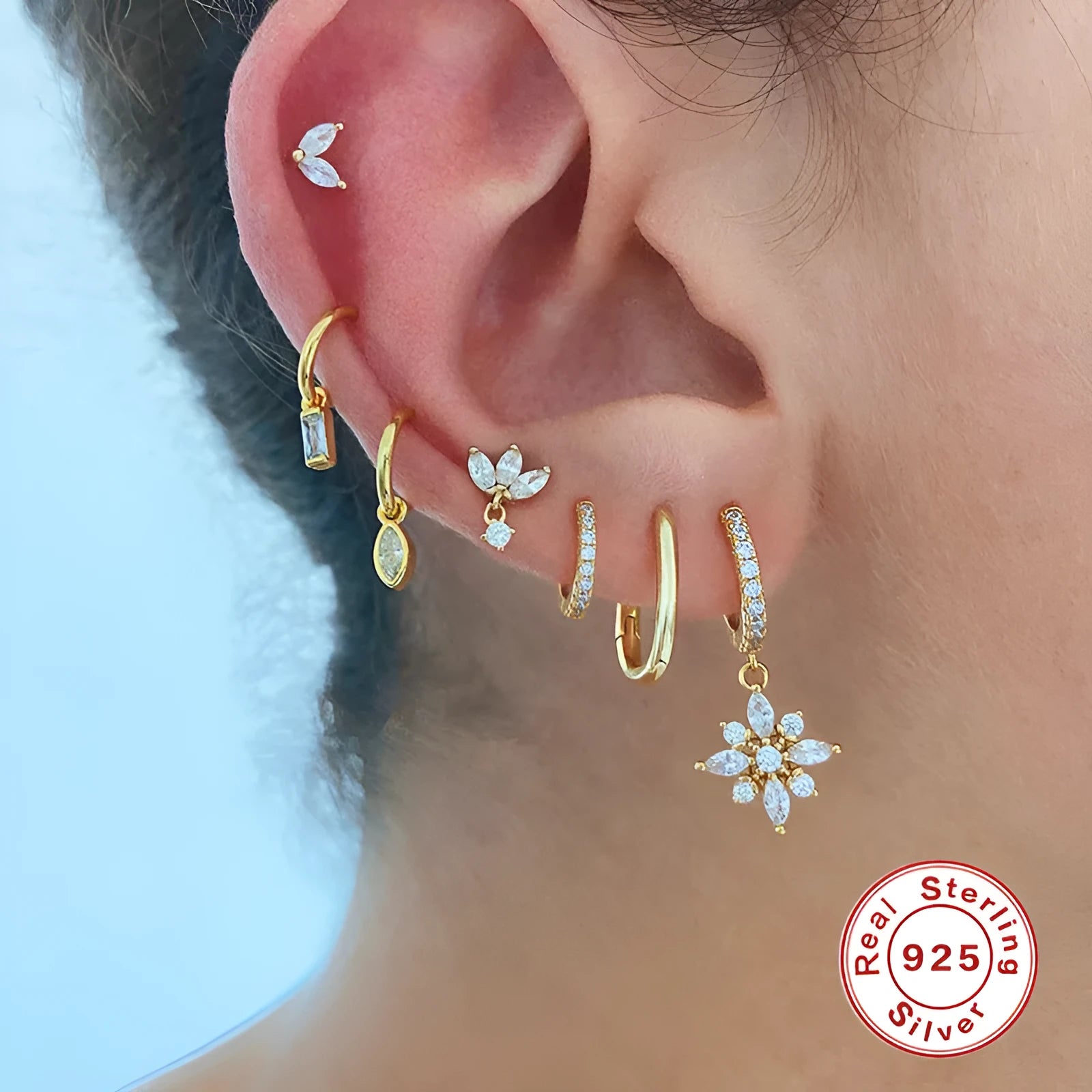 A pair of sterling silver snowflake pendant earrings with cubic zirconia stones on a white background.