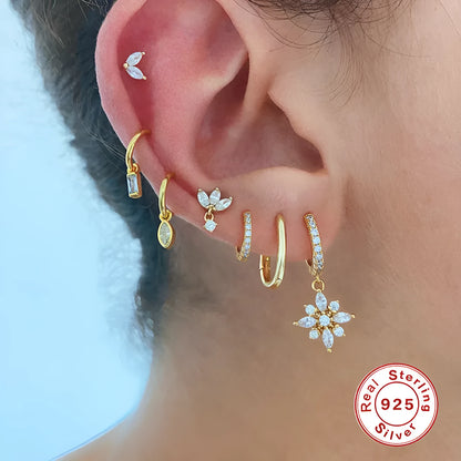 A pair of sterling silver snowflake pendant earrings with cubic zirconia stones on a white background.
