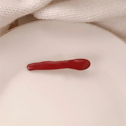 Red plastic hair clip with a 3D love heart and dots on a willow leaf-shaped base.