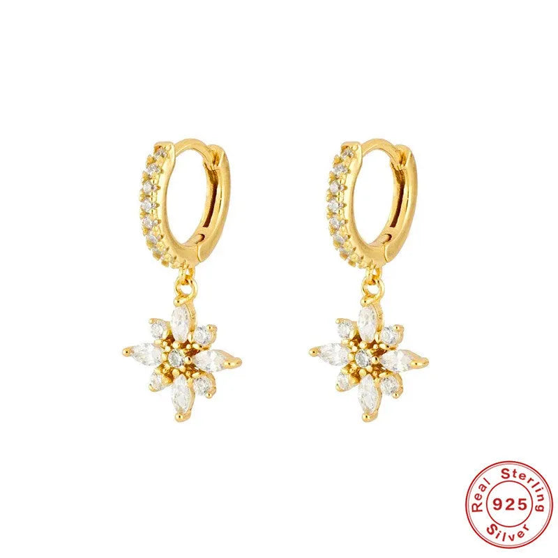 A pair of sterling silver snowflake pendant earrings with cubic zirconia stones on a white background.