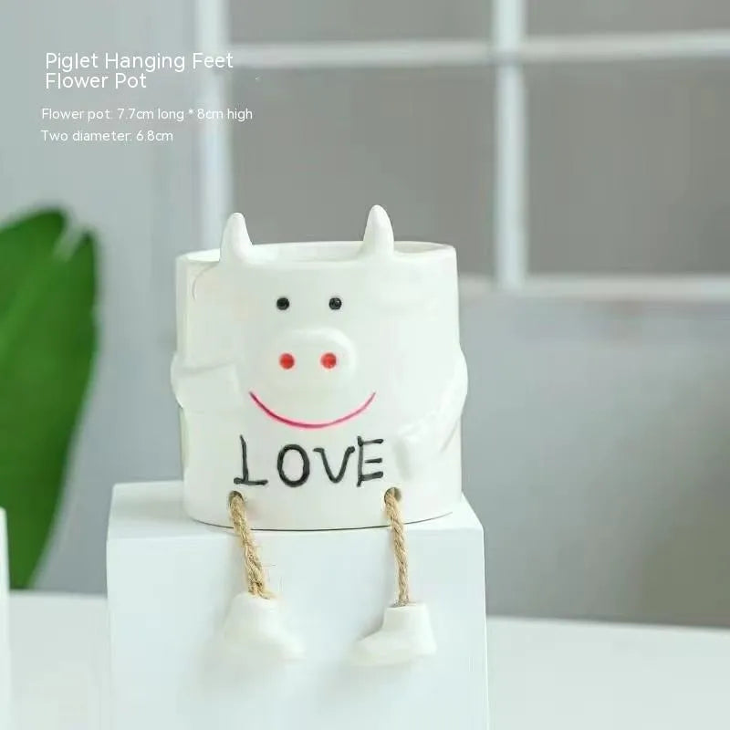 Ceramic hanging foot flowerpot for succulent plants with cartoon styling on desktop