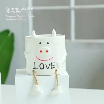 Ceramic hanging foot flowerpot for succulent plants with cartoon styling on desktop