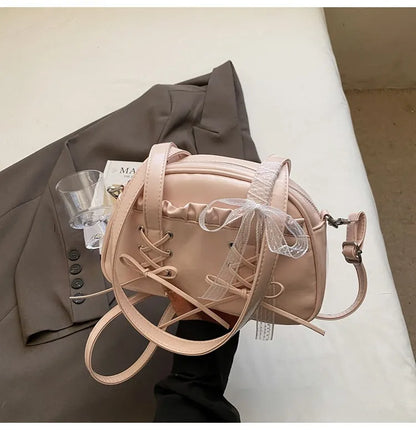 Milky white women's shoulder handbag with a large bandage bow and visible stitching, showing the internal phone pocket.