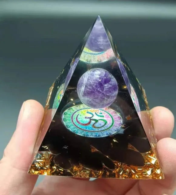 A small 6cm clear epoxy resin pyramid ornament containing pieces of natural crystal gravel on a flat surface.