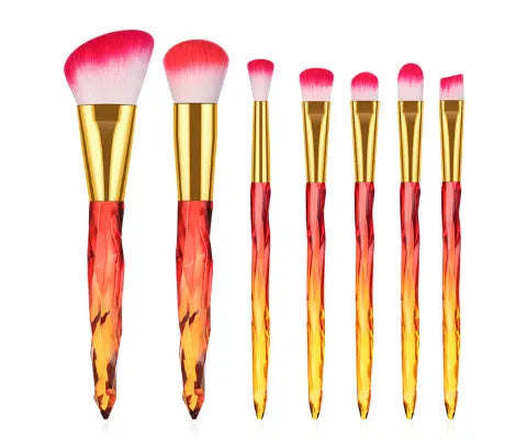 Ten clear crystal-handled foundation brushes with black synthetic bristles laid out on a surface.
