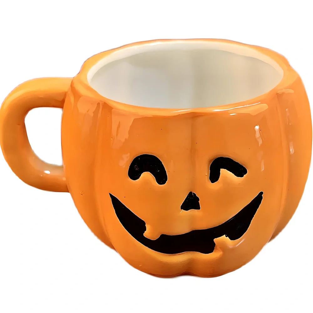 Orange ceramic Halloween pumpkin mug with cartoon face and included spoon on autumn table