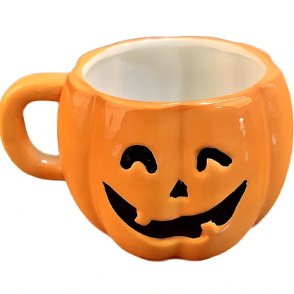 Orange ceramic Halloween pumpkin mug with cartoon face and included spoon on autumn table