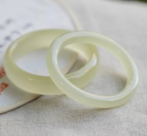 Ice-like silk jade bracelet with winding silk design and round bar beads on a wrist.