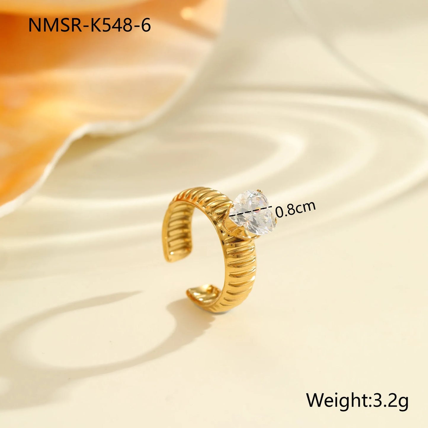 Gold electroplated stainless steel open mouth ring with geometric shapes and zircon inlay on a heart drop.