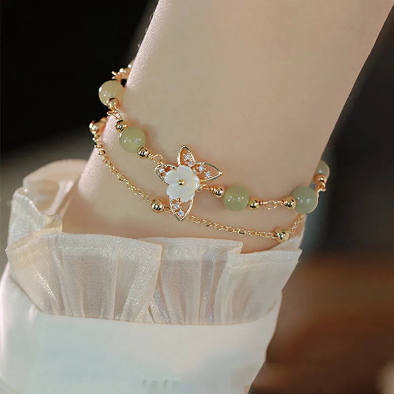 Women's shell flower butterfly bracelet in yellow gold with geometric design and hetian jade style charm.