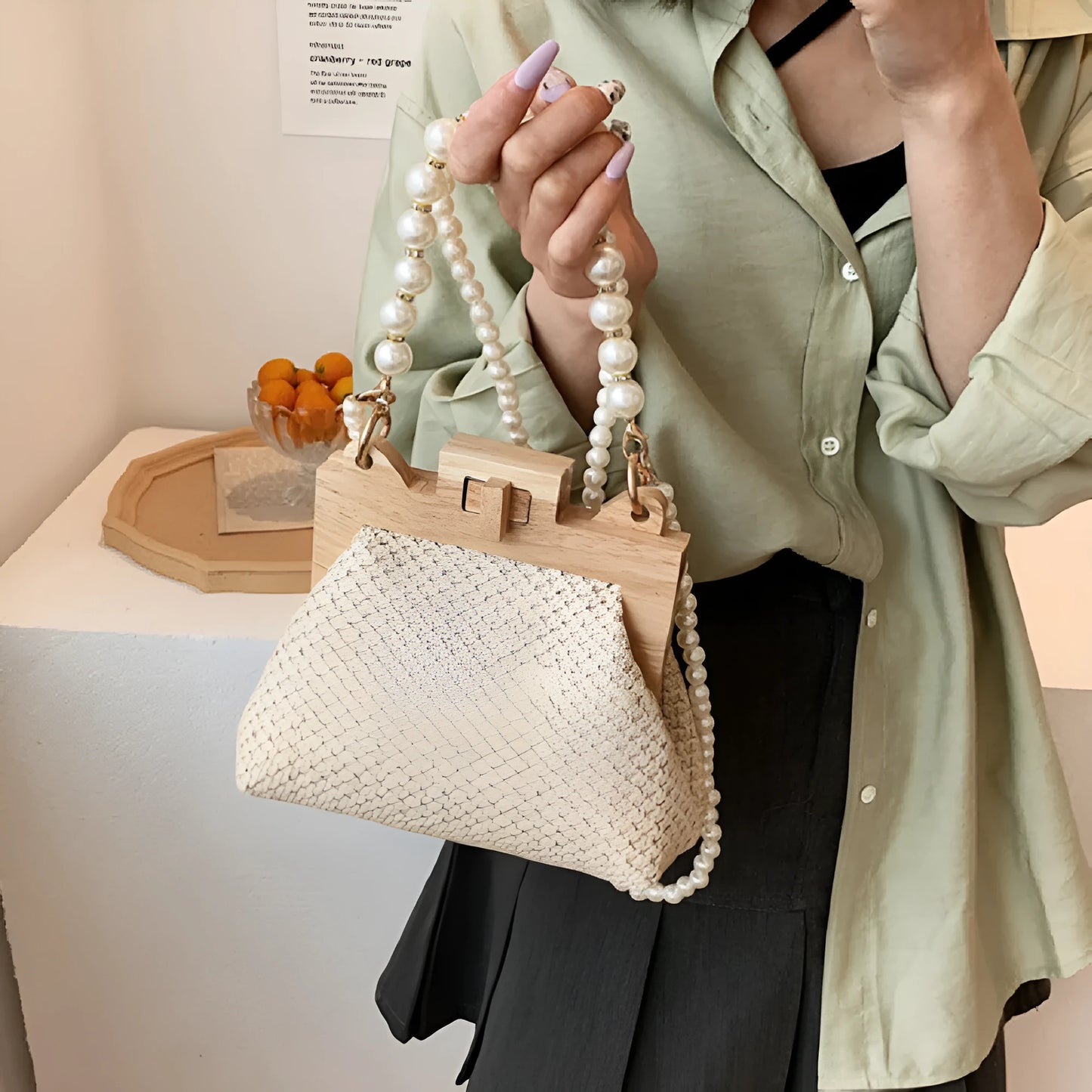 Women's beige straw woven shoulder bag with pearl chain strap, showing horizontal square shape and sewing line detail.