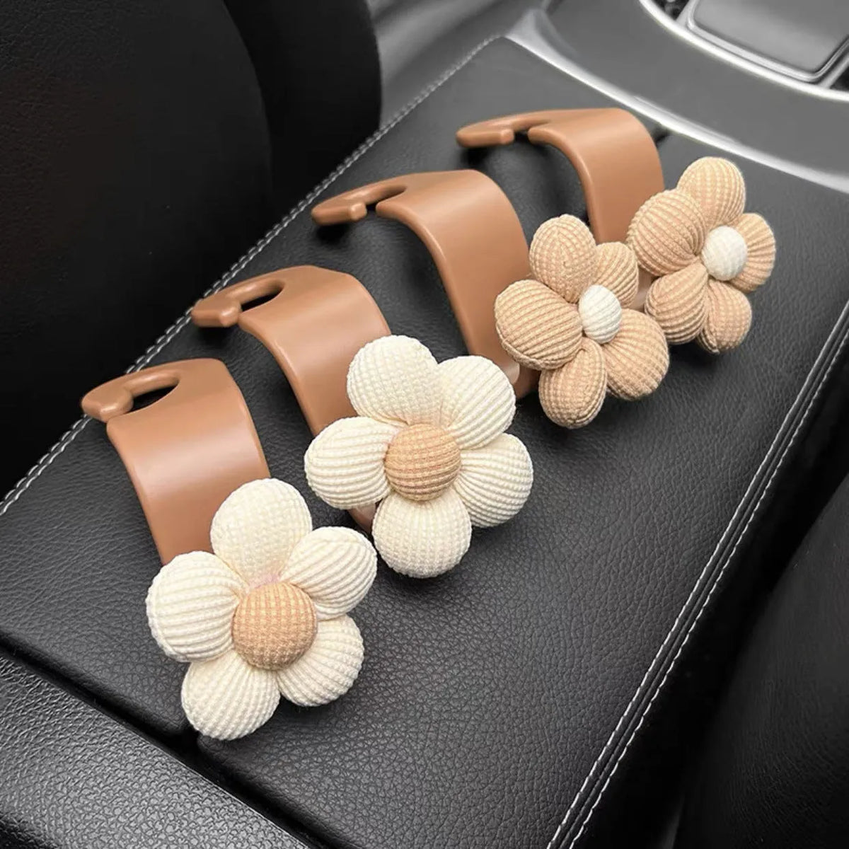 Khaki coloured plastic car seat hook with floral pattern for storage, shown at 11 by 5.5 cm.